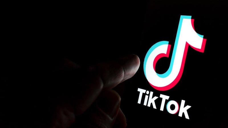 Un dedo a punto de presionar el botón de TikTok en el celular.
