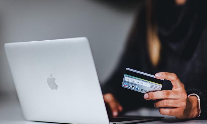 Mujer con su tarjeta de crédito frente a la notebook