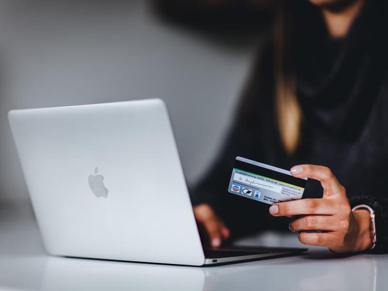 Mujer con su tarjeta de crédito frente a la notebook