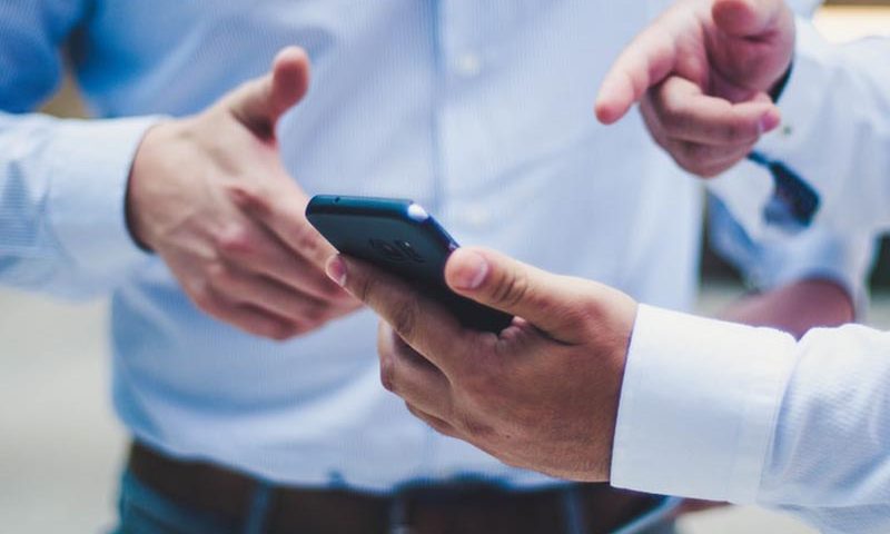 Conversación de dos hombres con un celular en la mano