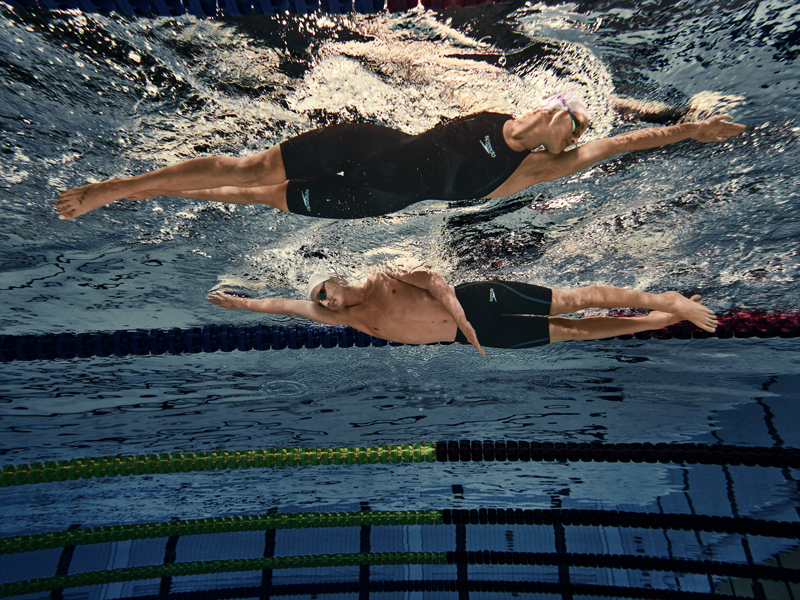 Nadadores hombre y mujer usando trajes de baño Speedo vistos desde abajo en el agua