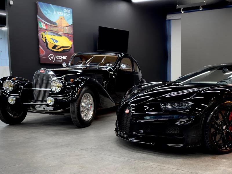 Dos autos Bugatti negros, uno antiguo y otro moderno deportivo.